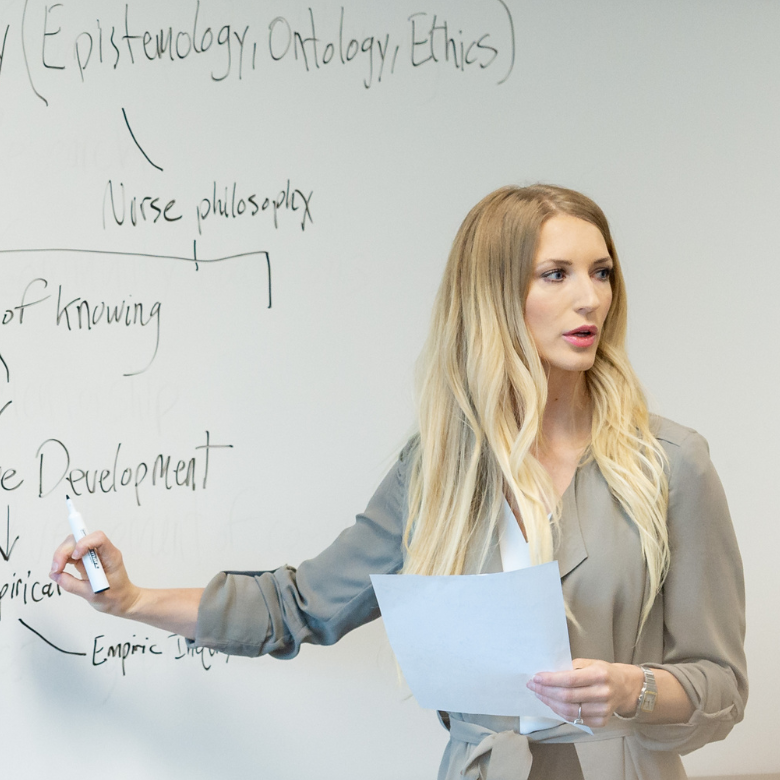 Dr. Laura Struik teaching in front of a whiteboard.