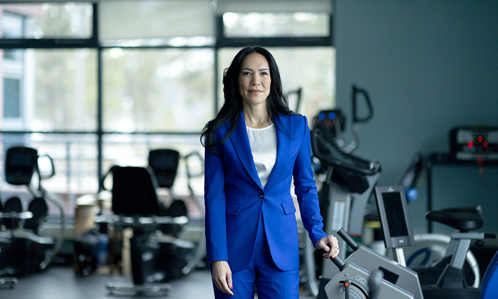 A photo of UBCO Professor Mary Jung standing in front of exercise equipment.