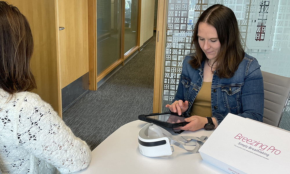 two people look at a new medical device that people can use at home to test their resting metabolic rate