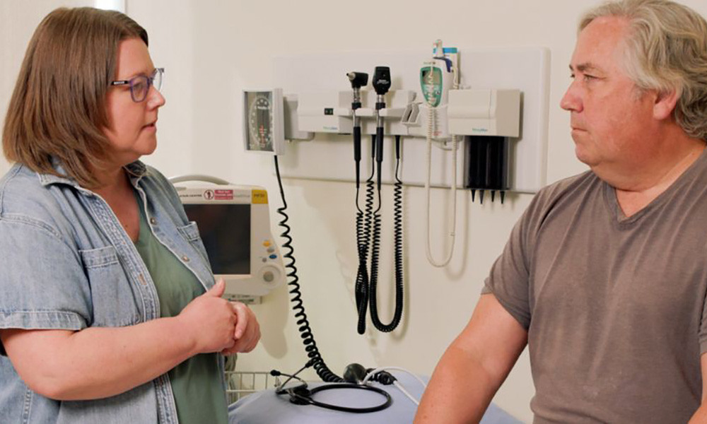 A nurse visits with a patient in an examination room 